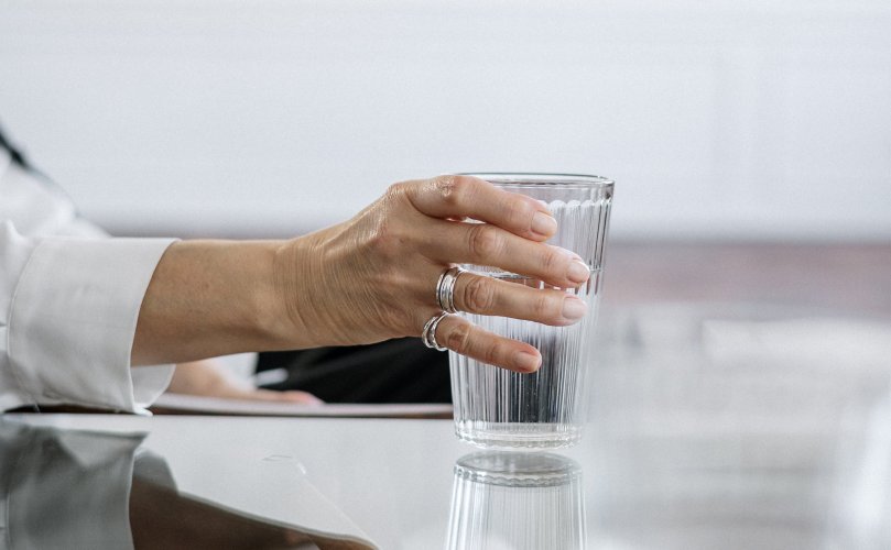 hand holding glass with water on table