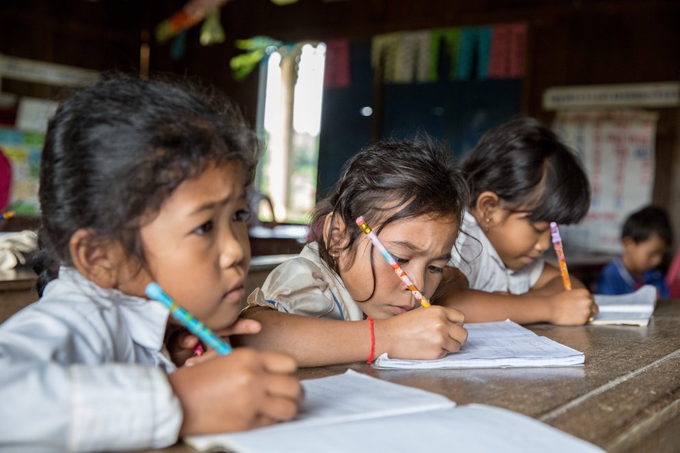 3 school girls writing in Cambodia