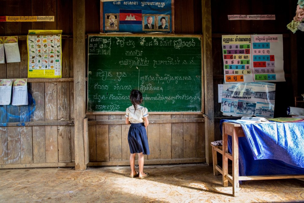 Ein Kind steht an einer Schultafel in Kambodscha