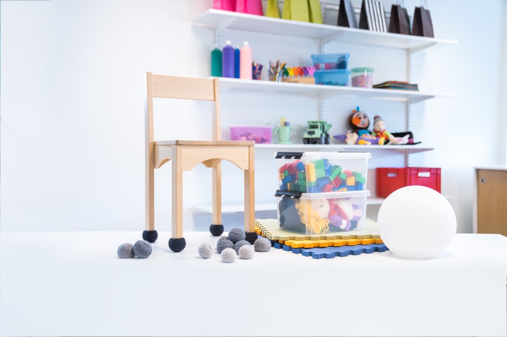 en trästol står på ett bord vid sidan av leksaker i olika färger
