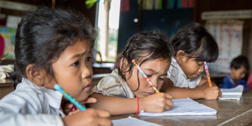 3 school girls writing in Cambodia